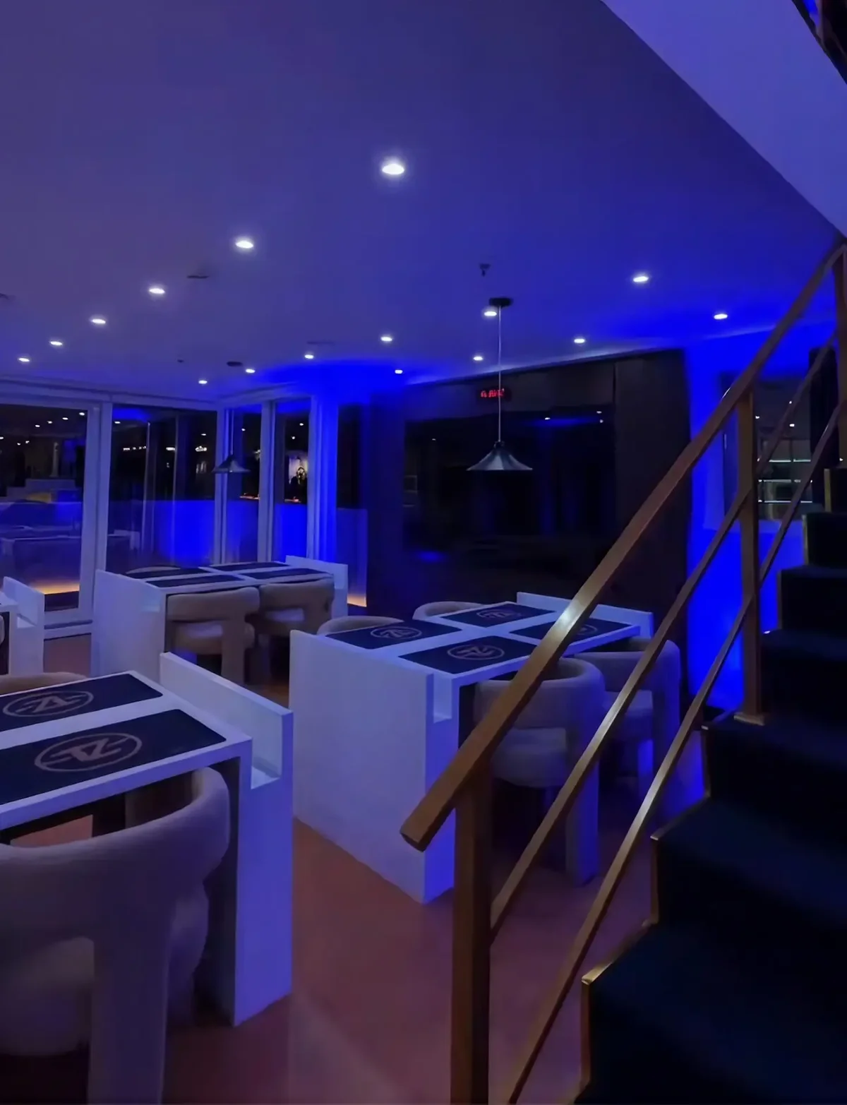 Salão da Tuzzy Cards Lounge com mesas de jogo e iluminação azul